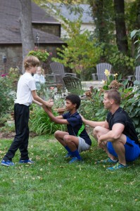 The spotter stands with his feet staggered for support, and then I am seen here cue'ing the squatter ("Big D") to maintain a tall, strong spine as he sits back and down. Switch on and off holding the position for 30-60 seconds each person for two sets.